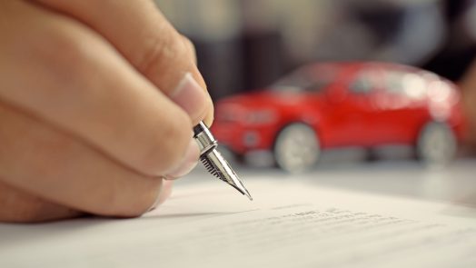 Man signing car insurance document. Writing signature on contract or agreement. Buying or selling new or used vehicle.