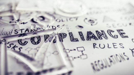 Transparent check mark over compliance related icons and words handwritten on white papers