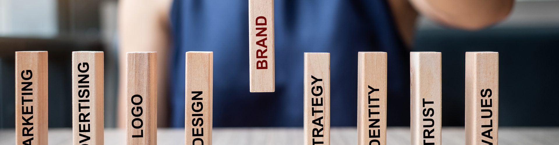 Businesswoman hand placing or pulling wooden Dominoes with BRAND text. and Marketing, Advertising, Logo, Design, Strategy, Identity, Trust and Values. Product development concept