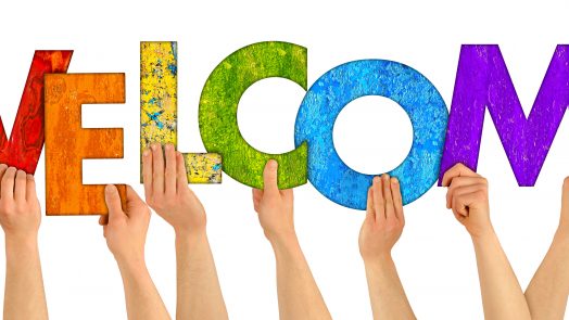 hands holding up colorful wooden letters shaping the word welcome isolated on white background