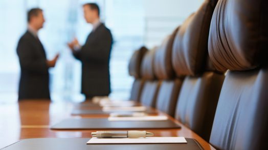 Side view of two blurred businessmen talking in conference room