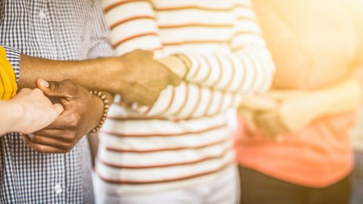 Creative team meeting hands together in line. Young people in casual clothes are holding hands. Unity and teamwork concept.