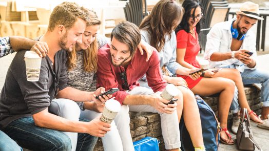 Multiracial millennials group using smart phone at city college backyard - Young people addicted by mobile smartphone - Technology concept with connected trendy friends - Warm vibrance sunshine filter