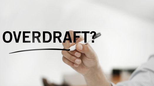 businessman writing on a virtual board quoting “Overdraft?”