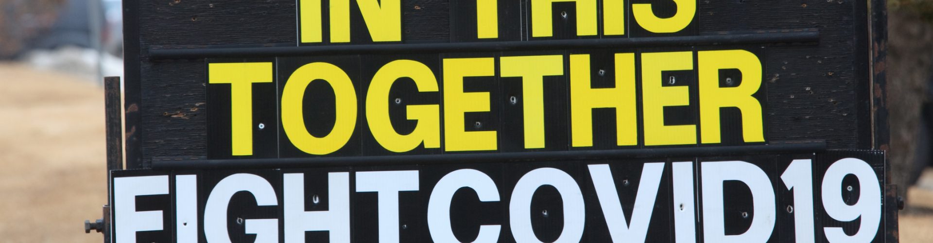 A sign or billboard in front of a business that states we are all in this together fight Covid-19.