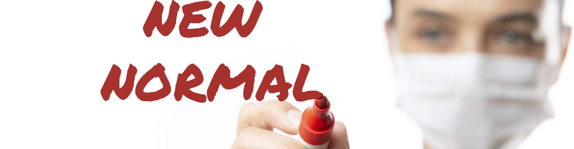 Masked woman writing New Normal with felt tip pen.