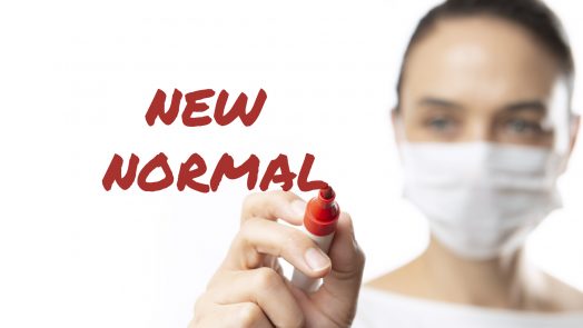 Masked woman writing New Normal with felt tip pen.