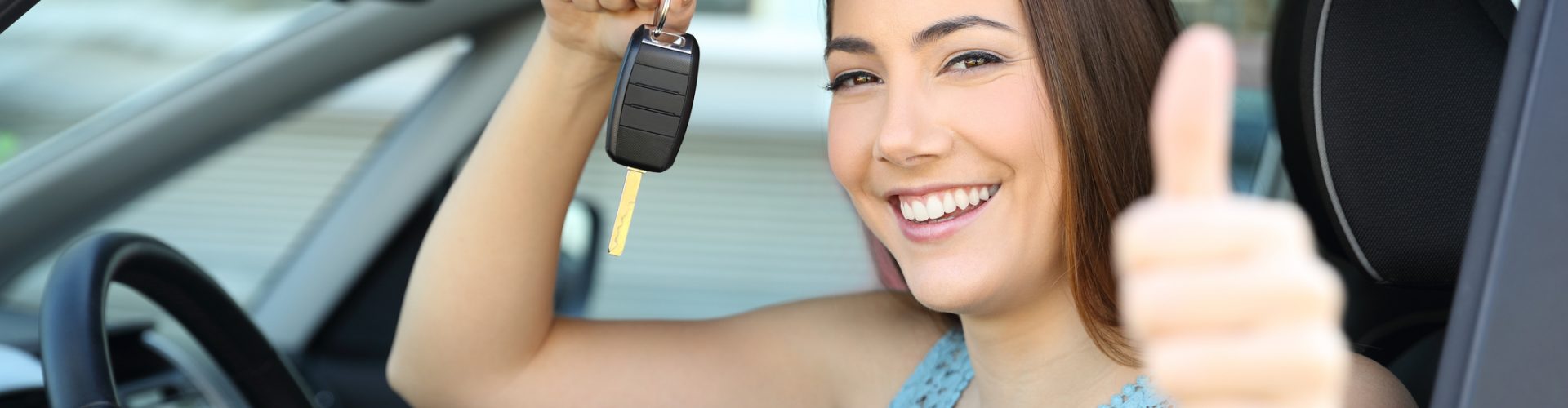 Happy car owner with a key and thumbs up