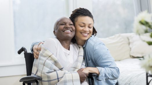 Woman embraces her wheelchair-bound mother