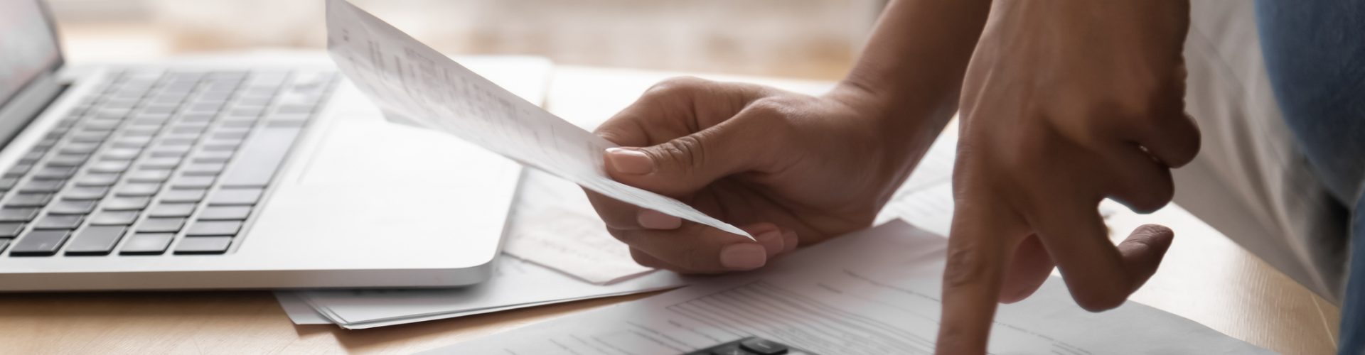 African woman holding paper bills using calculator, close up view